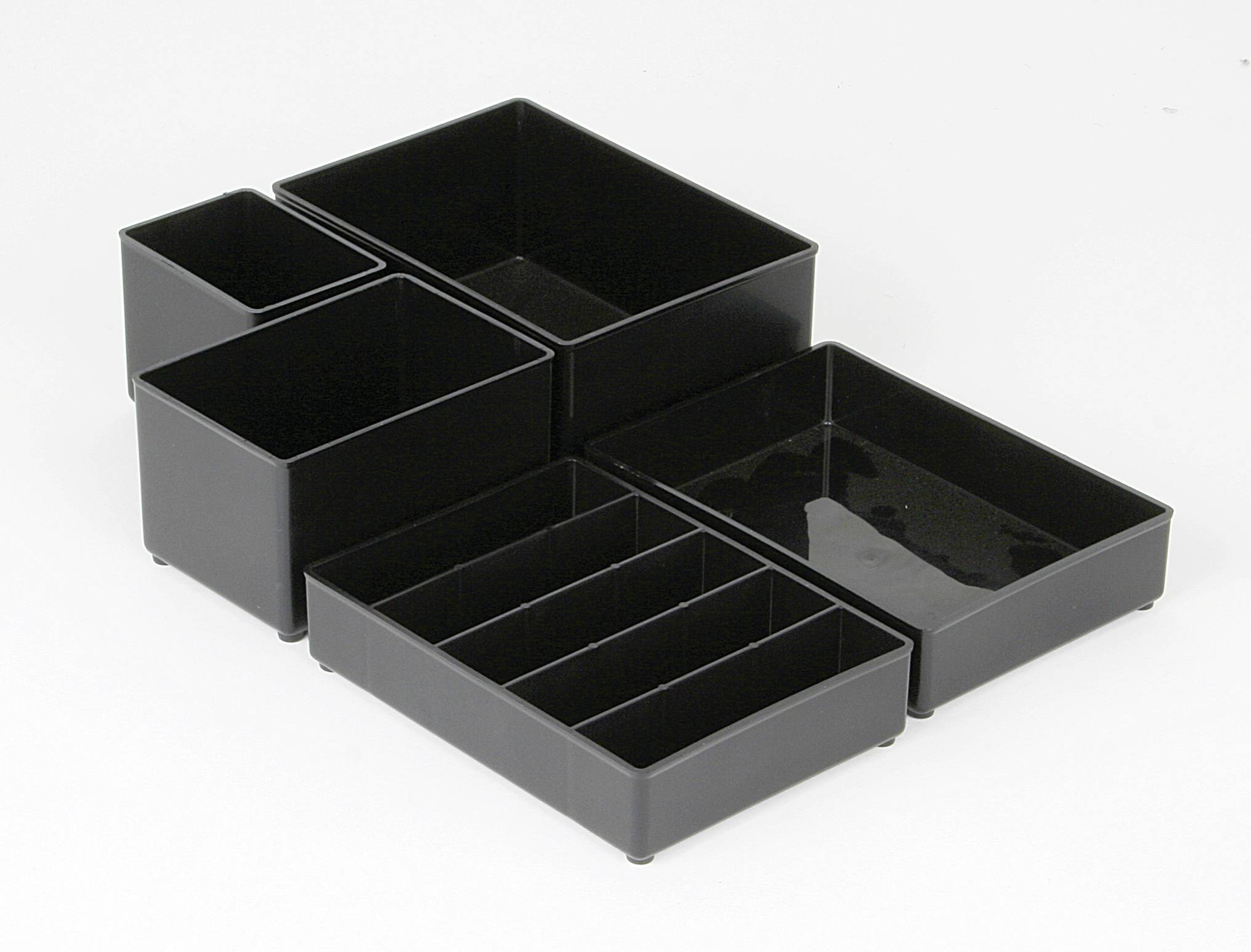 Boîtes de rangement en plastique noir, de forme rectangulaire, disposées en groupe. Idéales pour les accessoires de bureau ou de bureau.
