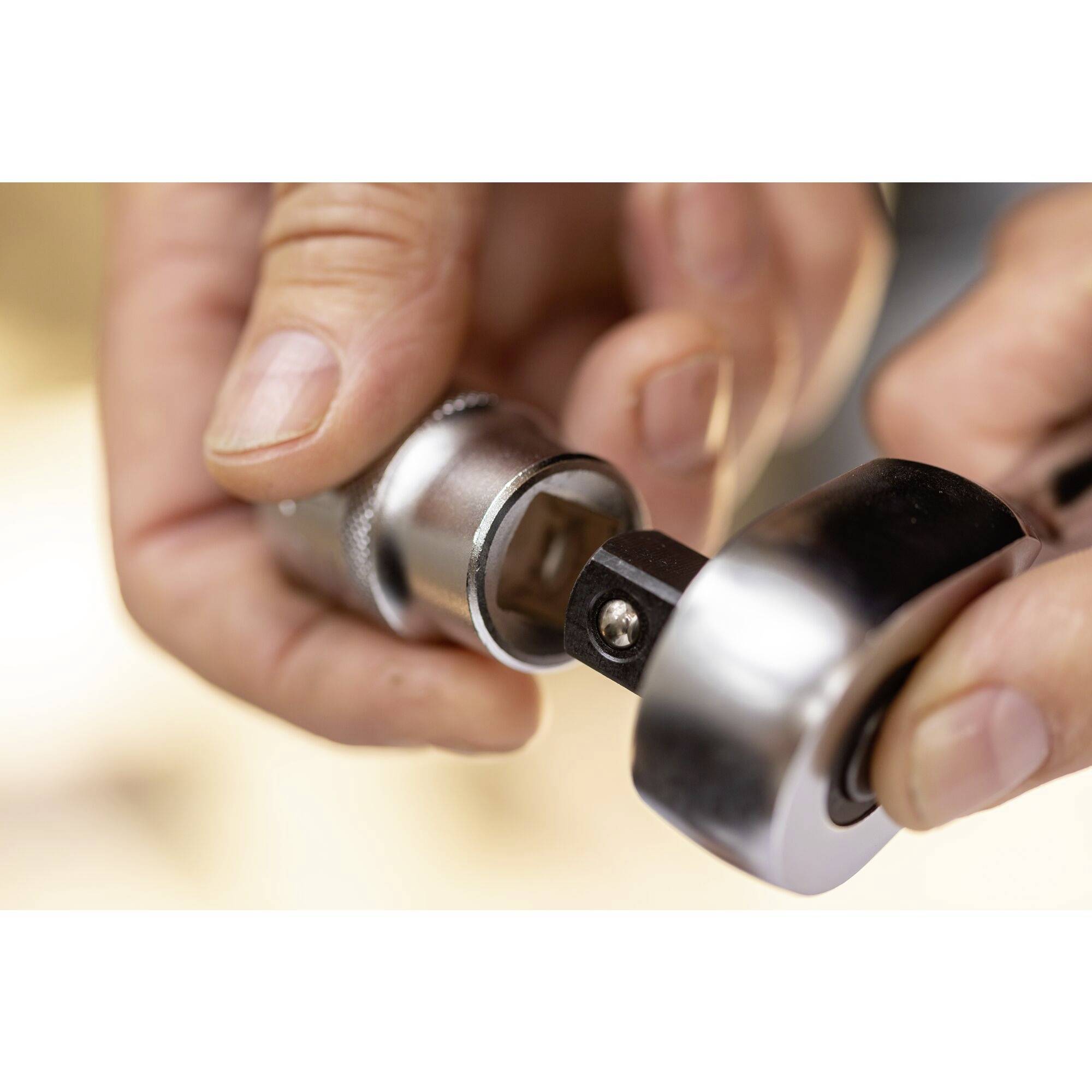 Gros plan sur des mains assemblant une clé à cliquet et un écrou. Symbolisant un travail mécanique ou un montage d'outils.