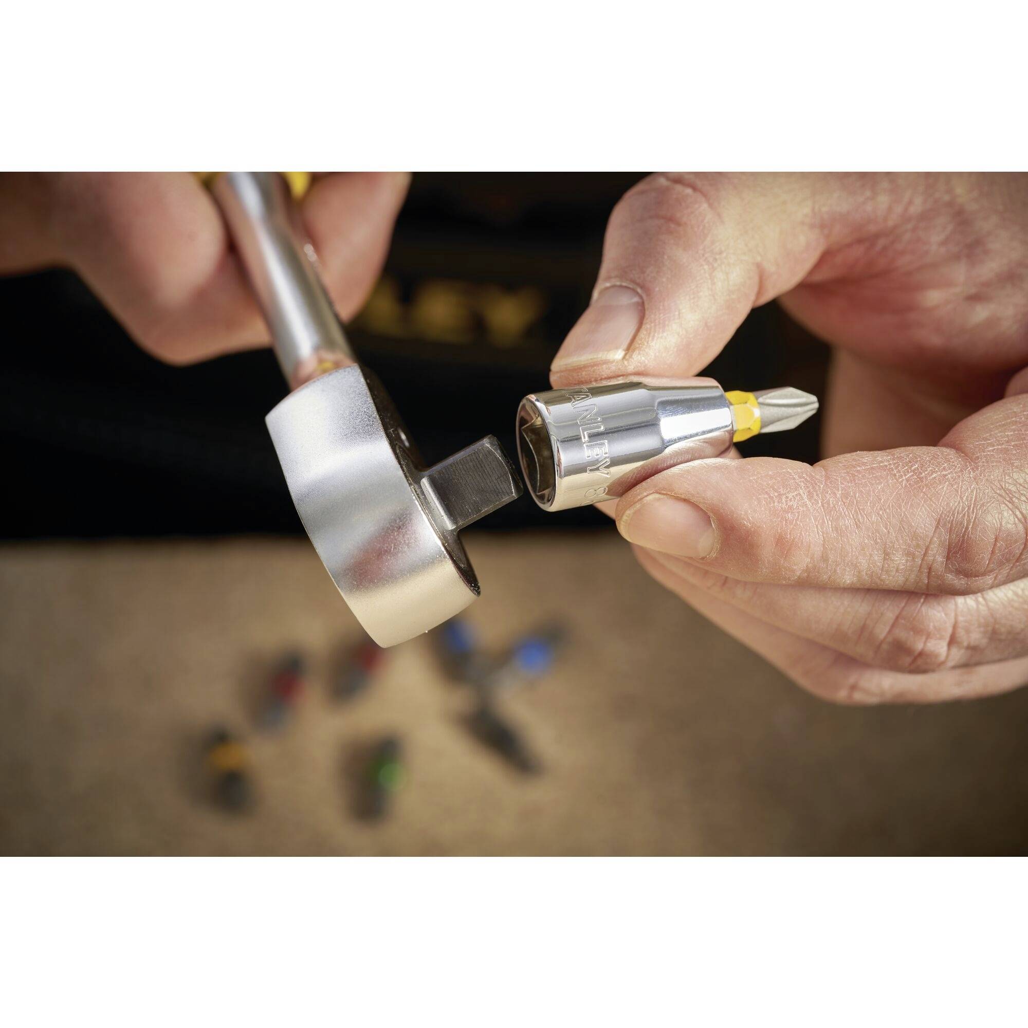 Deux mains tiennent un tournevis et une clé, concentrées sur l'ajustement d'un embout de vis.