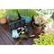 Poste de travail de jardinage avec une boîte à outils, des gants et une pelle à côté de plantes en pots sur une terrasse en bois.