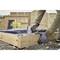 Une personne construit une boîte rectangulaire en bois à l'extérieur. Elle utilise un outil électrique pour fixer les planches de bois.