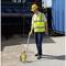 Un ouvrier mesure une distance avec un odomètre sur un chantier de construction. Il porte des vêtements de sécurité et un casque de protection.