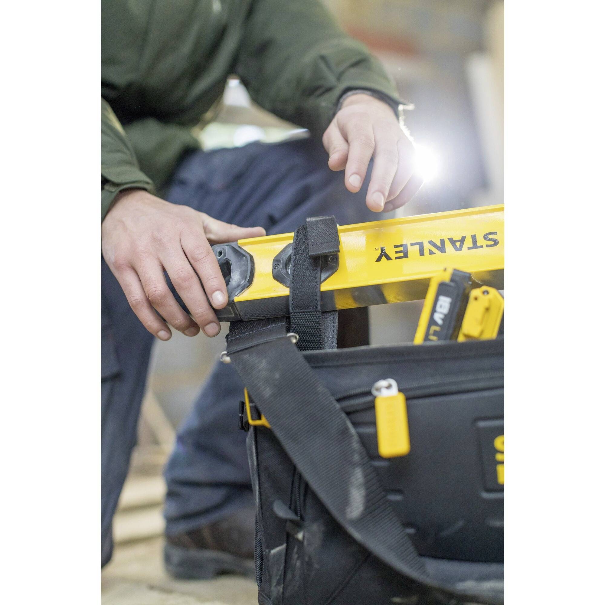 Une personne tient un niveau à bulle au-dessus d'un coffret à outils dans un environnement de chantier.