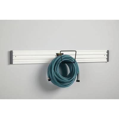 Un tuyau d'arrosage vert est soigneusement suspendu à un support blanc fixé au mur, conçu spécifiquement pour les accessoires de jardin.