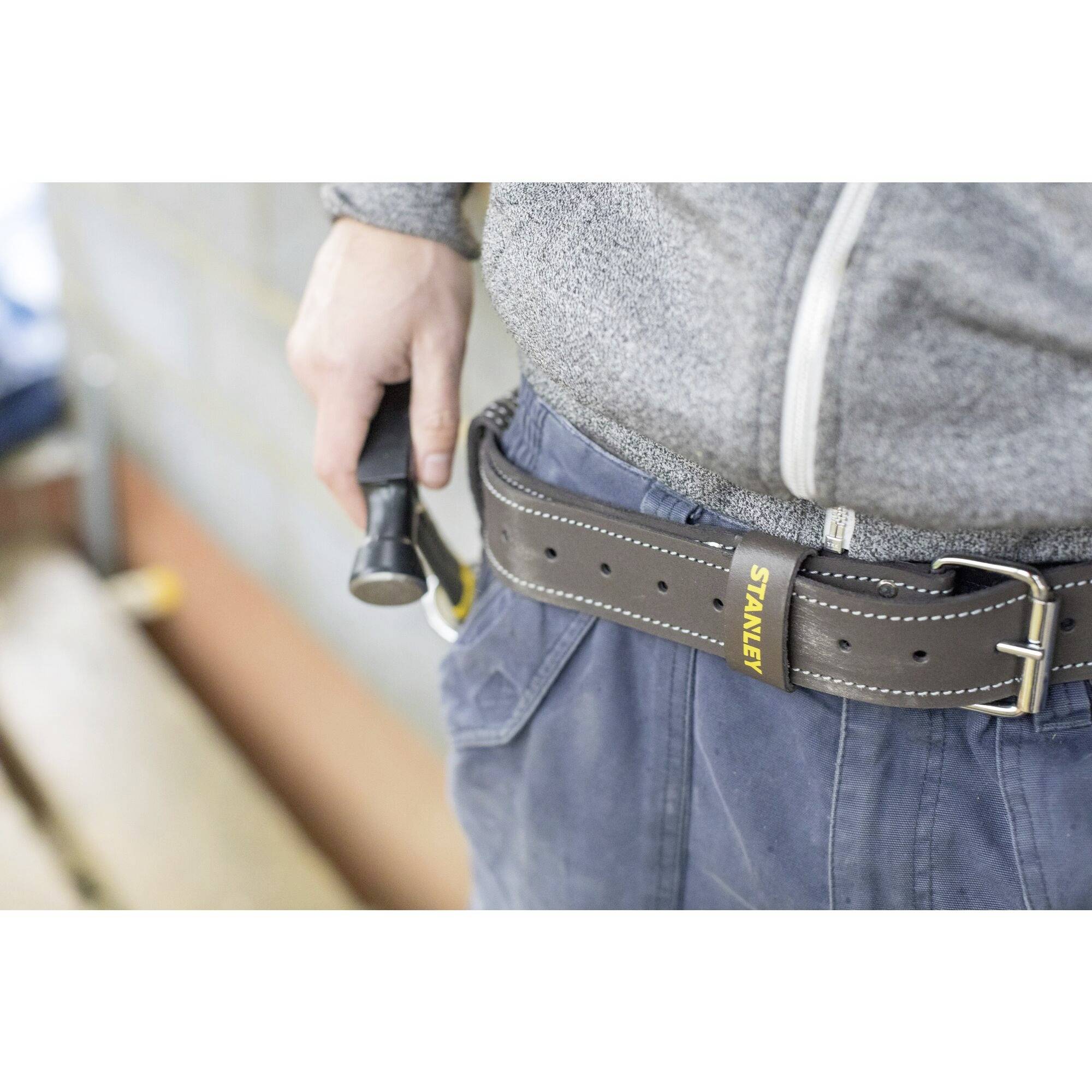 Une personne porte une ceinture portant l'inscription 'Stanley', à laquelle est suspendu un marteau.