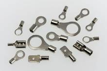 Différents embouts de câble et connecteurs métalliques de différentes tailles, répartis sur une surface claire.