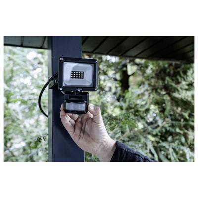 Main manuelle d'un projecteur avec détecteur de mouvement monté sur un poteau de porche à l'extérieur.