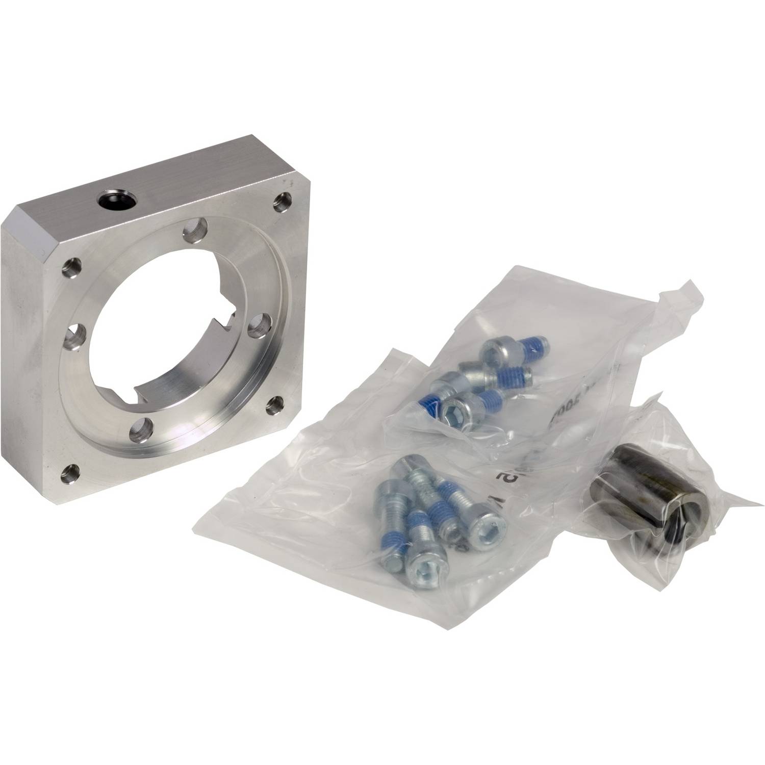 Un morceau de métal carré avec une ouverture circulaire est posé à côté de deux sachets en plastique scellés contenant des vis et des accessoires.