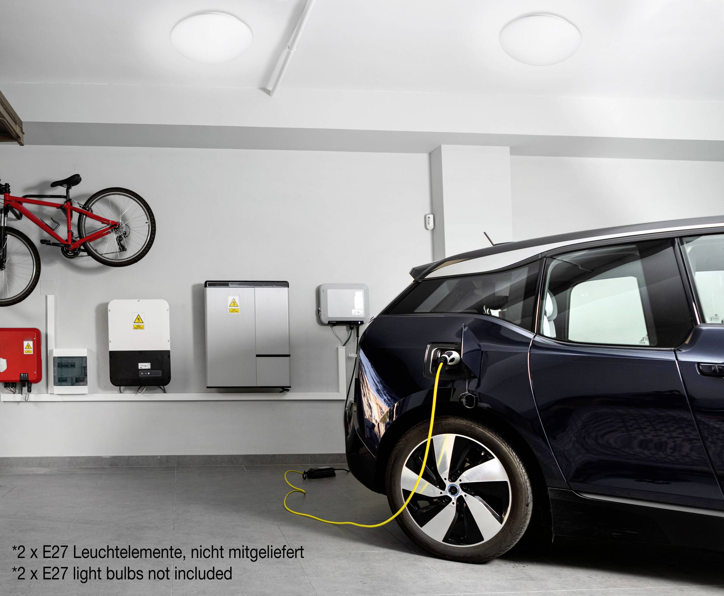 Une voiture électrique est en charge dans un garage moderne. Plusieurs appareils et un vélo sont fixés au mur.