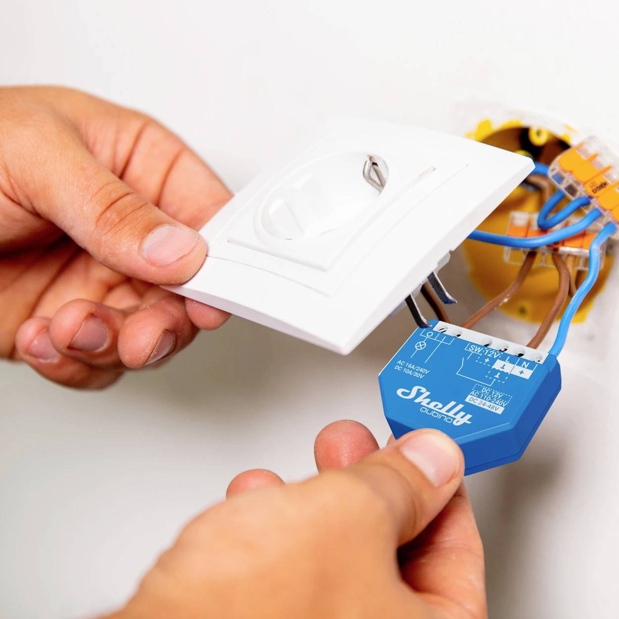 Une personne installe un interrupteur électrique et connecte les fils, démontrant le processus d'installation d'un interrupteur sur un mur.