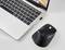 Un ordinateur portable ouvert avec un clavier rétroéclairé est posé sur une table blanche. À côté se trouve une souris sans fil noire.