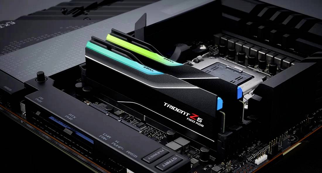 Deux barrettes de RAM Trident Z5 installées sur une carte mère, à l'intérieur d'un ordinateur. Elles sont noires avec des bandes bleues et vertes.