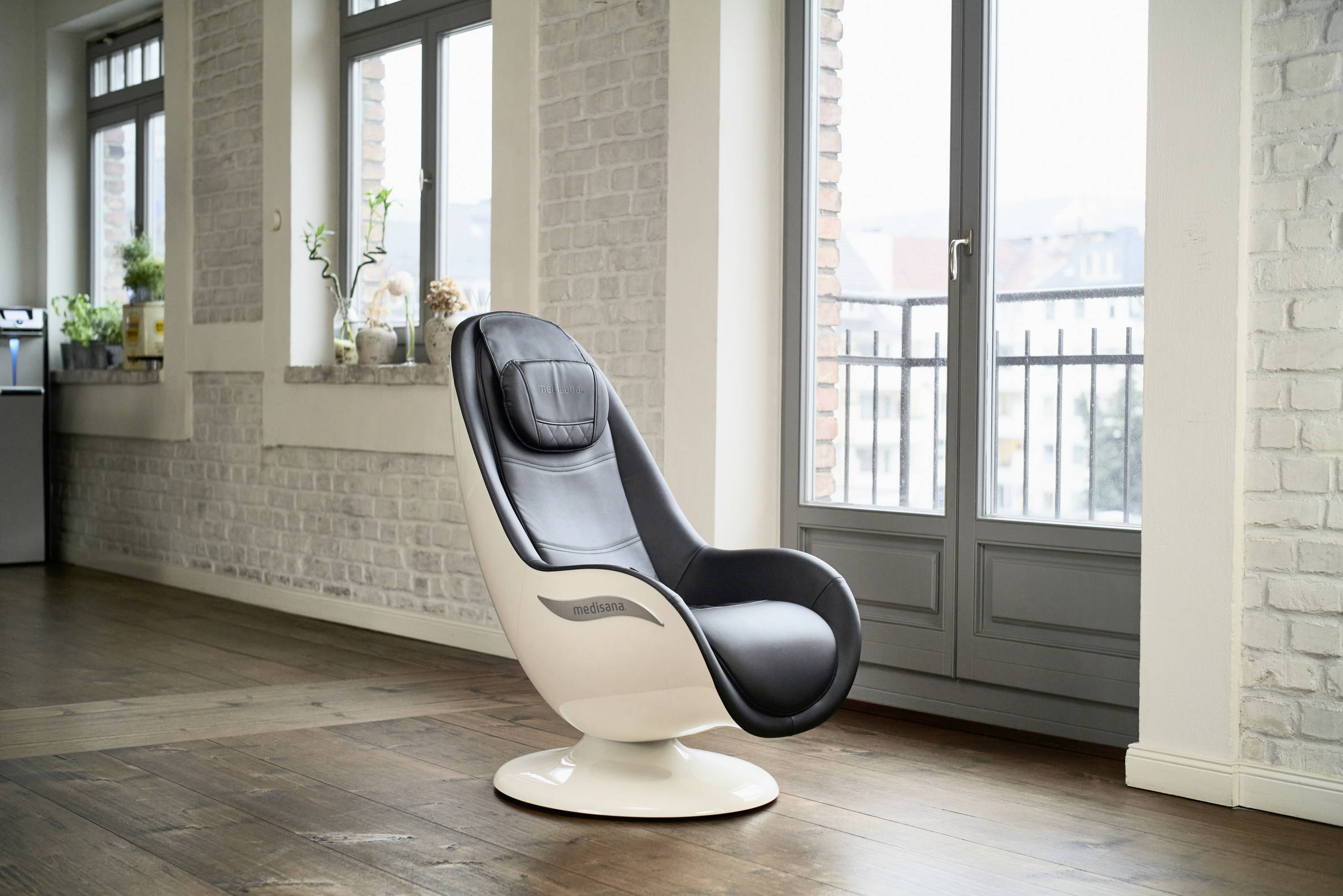 Un fauteuil moderne noir et blanc est placé dans une pièce élégamment aménagée avec de grandes fenêtres et un sol en bois.
