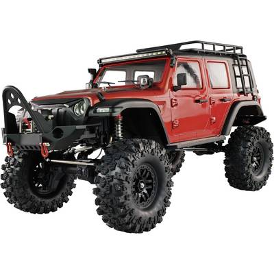 Un tout-terrain rouge modifié, équipé de gros pneus tout-terrain et d'un porte-bagages de toit robuste, prêt à affronter un terrain difficile.