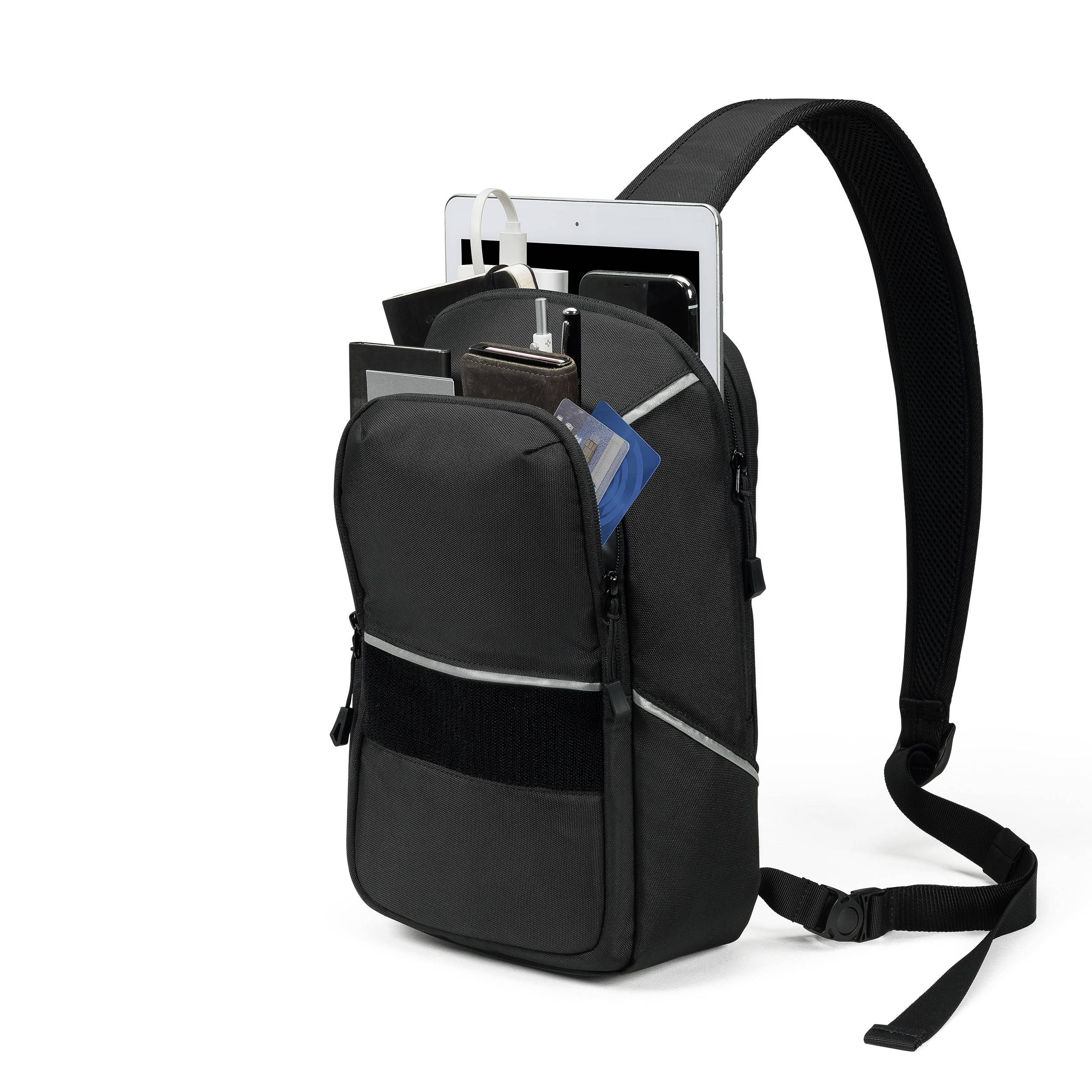 Un sac à dos noir est ouvert et montre une tablette, un carnet, deux stylos et un téléphone portable. La bandoulière est visible.