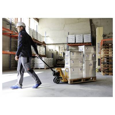Un ouvrier dans un entrepôt tire un transpalette chargé de boîtes métalliques empilées. Des étagères avec des boîtes supplémentaires sont en arrière-plan.
