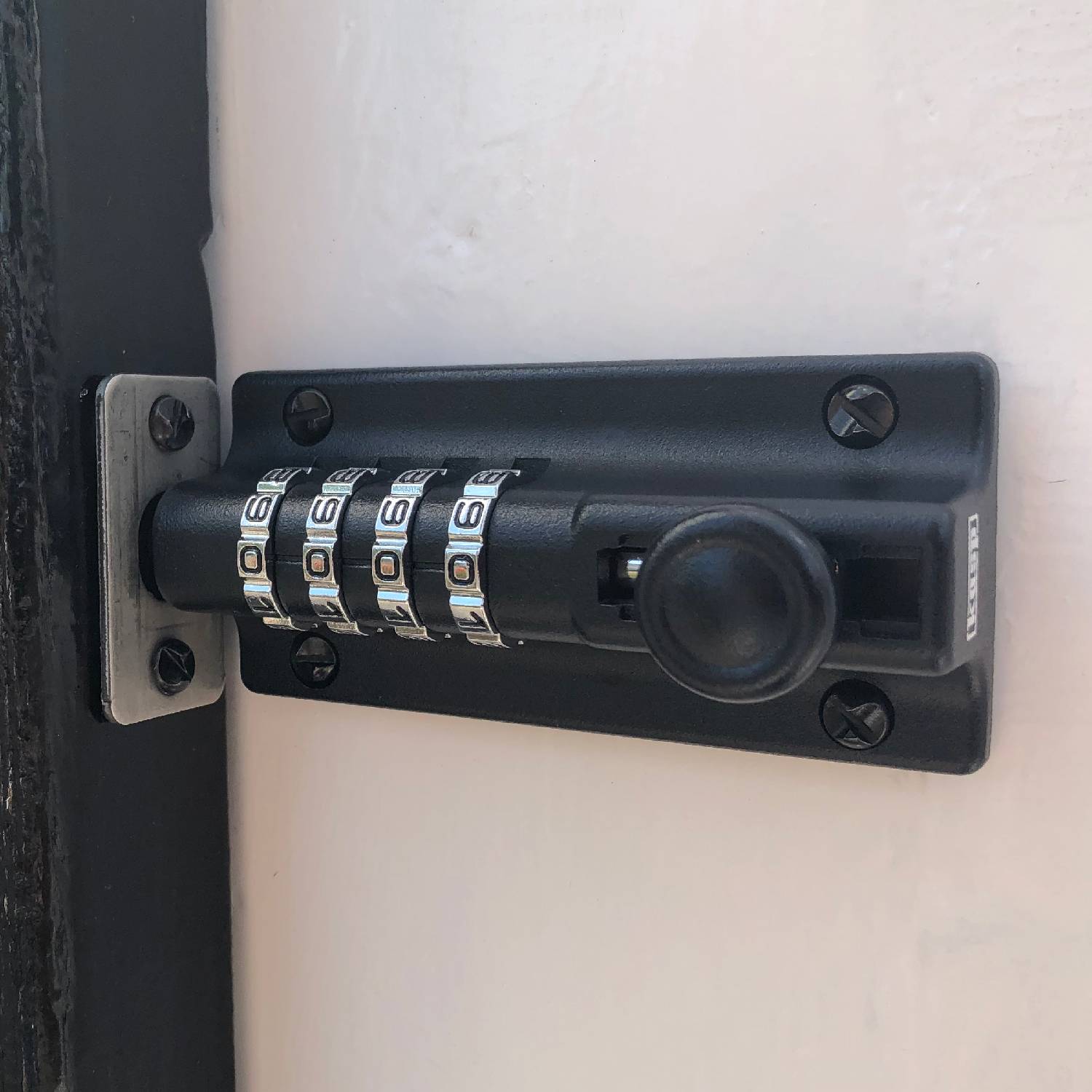 Un cadenas numérique noir à quatre chiffres sur une porte. Combinaison réglée sur '0000'.