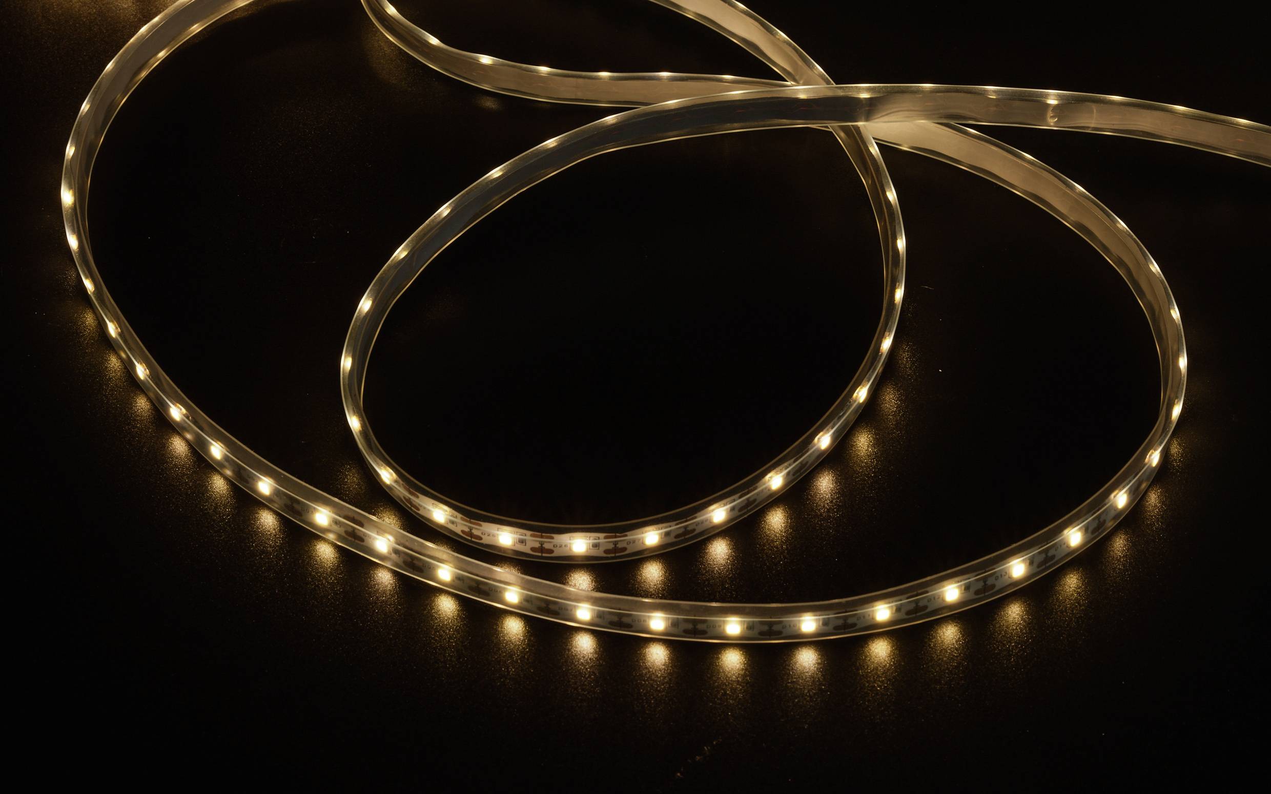 Une barre lumineuse à LED repose sur un fond sombre. Elle est sinueuse et dispose de petites lumières réparties uniformément.