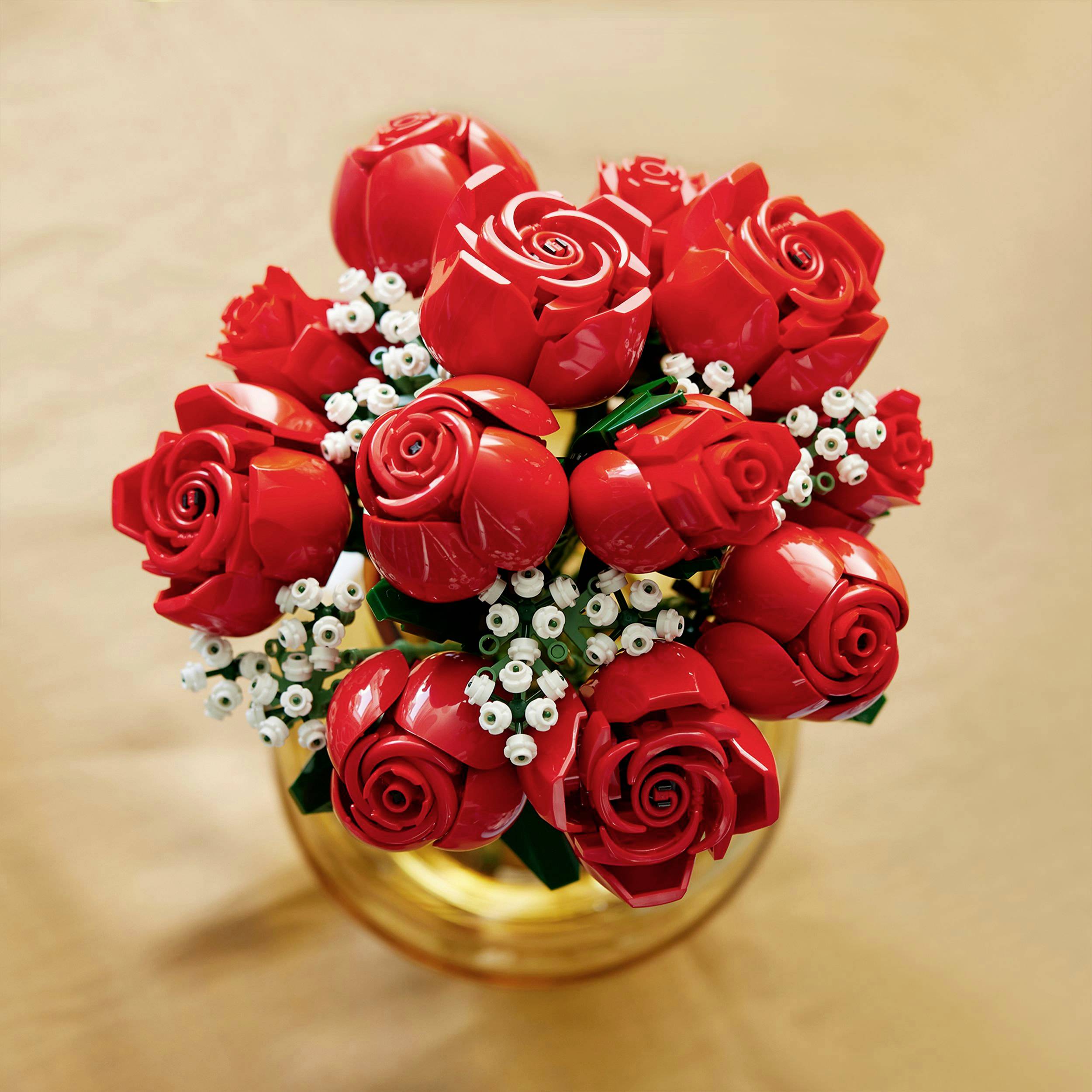 Un bouquet de roses rouges en briques Lego dans un vase, conçu avec de nombreux détails, sur un fond doré.