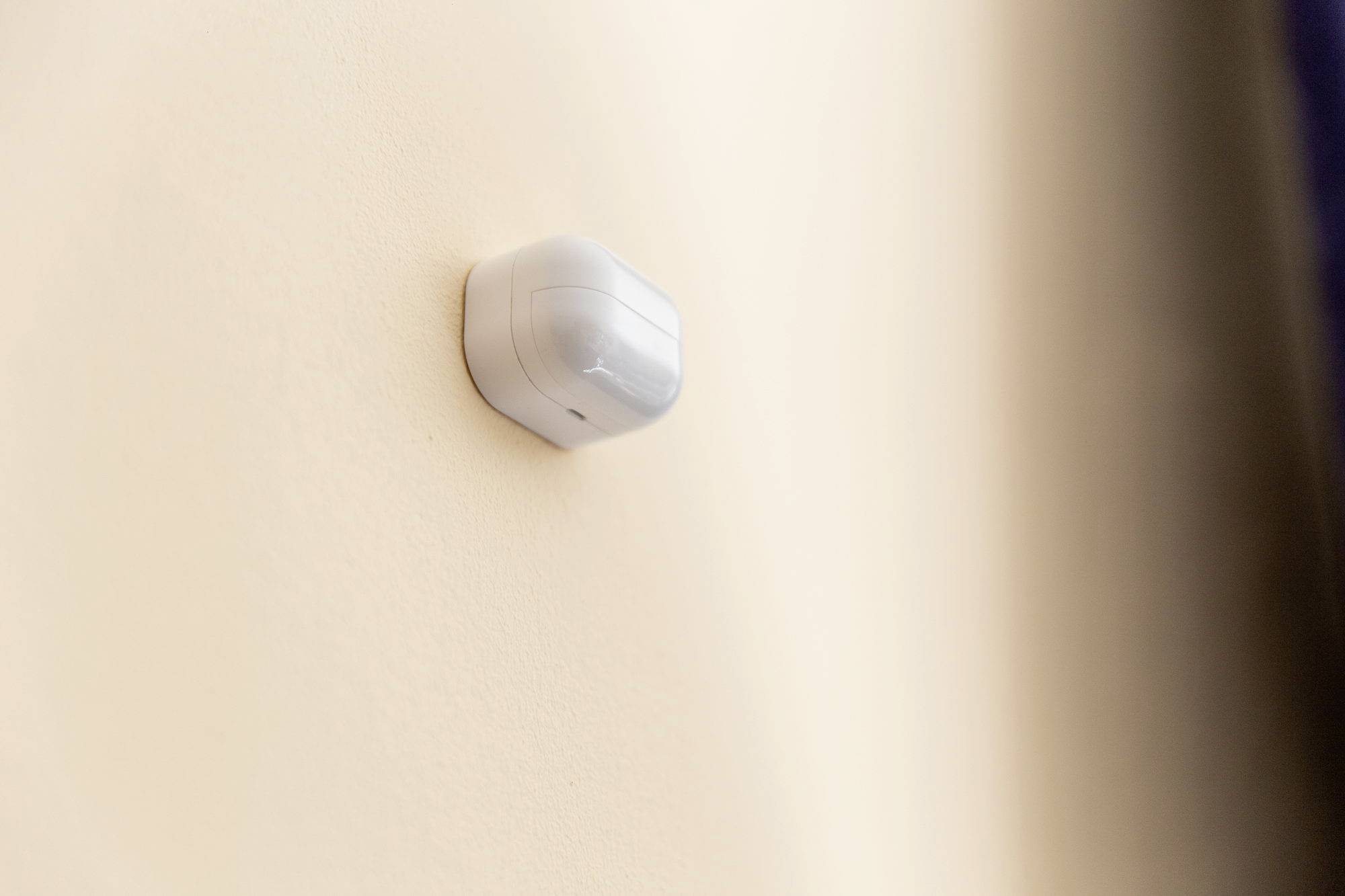 Un détecteur de mouvement sur un mur couleur crème.