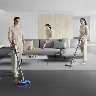 Trois personnes aspirent de manière synchronisée une pièce aménagée de façon moderne et minimaliste, avec un canapé gris et une table basse.