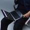 Une personne est assise sur une chaise et utilise un ordinateur portable en mode tablette. L'écran affiche une application avec une interface sombre.