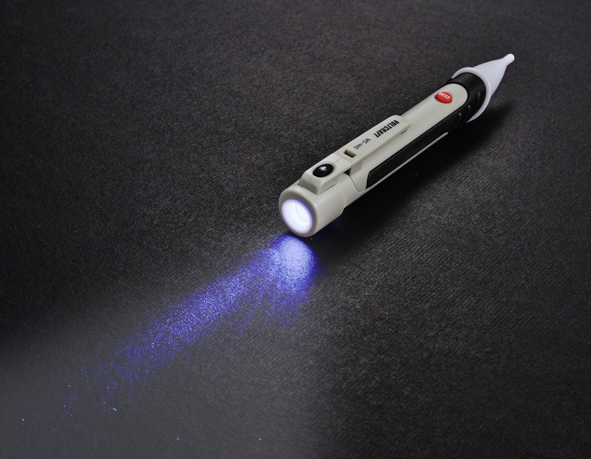 Un stylo lampe de poche est posé sur un fond sombre. Il émet une lumière bleue à travers l'objectif.