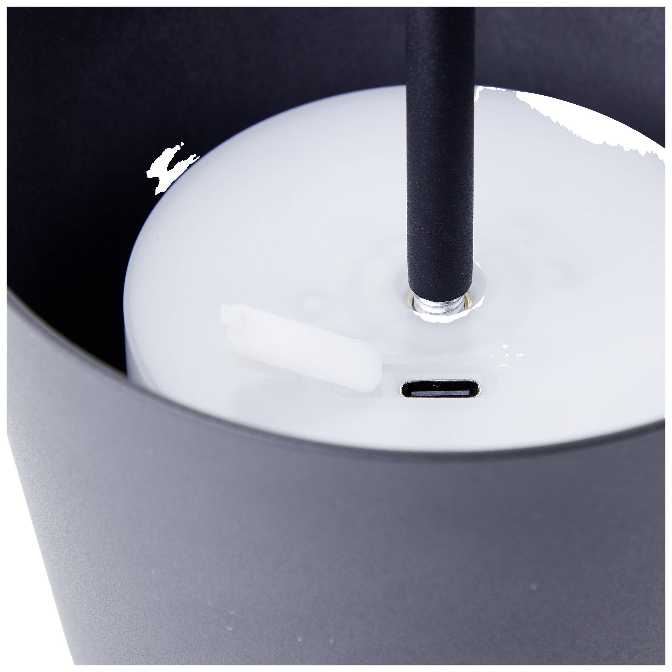 Appareil noir et rond avec une paille et un port USB-C sur un fond blanc. L'appareil est partiellement recouvert d'un liquide blanc.