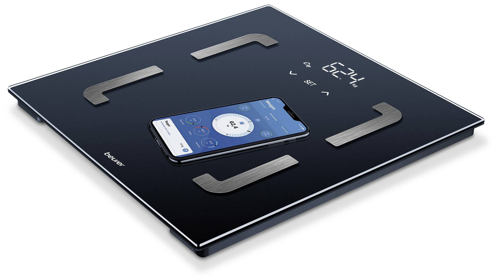 Balance numérique avec un smartphone sur sa surface. L'écran affiche '62,4'. La balance mesure les valeurs d'analyse corporelle.