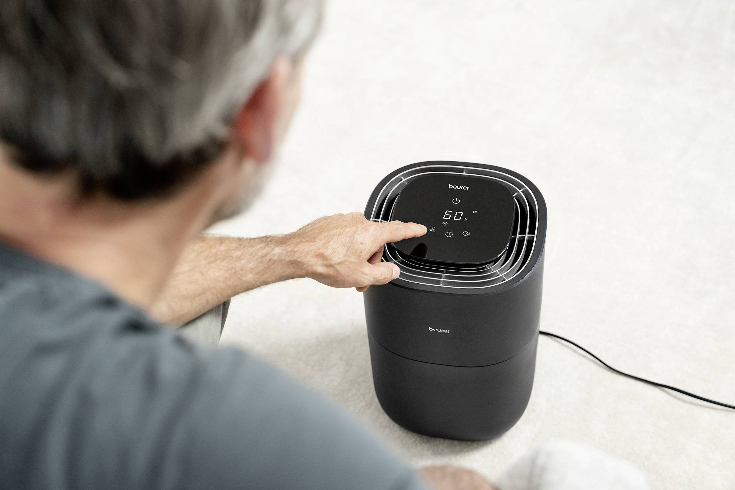 Un homme manipule un appareil électrique noir avec un affichage. L'appareil est posé au sol et indique '60'.