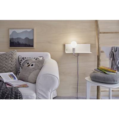 Salon confortable avec un canapé blanc, un coussin gris à motif de hibou, un livre ouvert et une lampe de table. Une chaise supporte des livres.