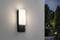 Applique murale au design moderne illuminant un mur extérieur dans un environnement de jardin nocturne.