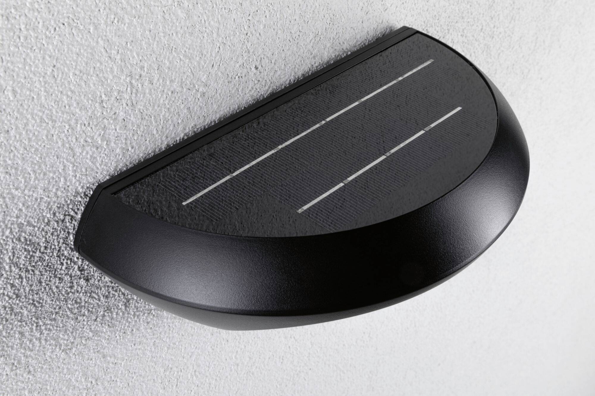 Luminaire extérieur alimenté par énergie solaire fixé au mur.