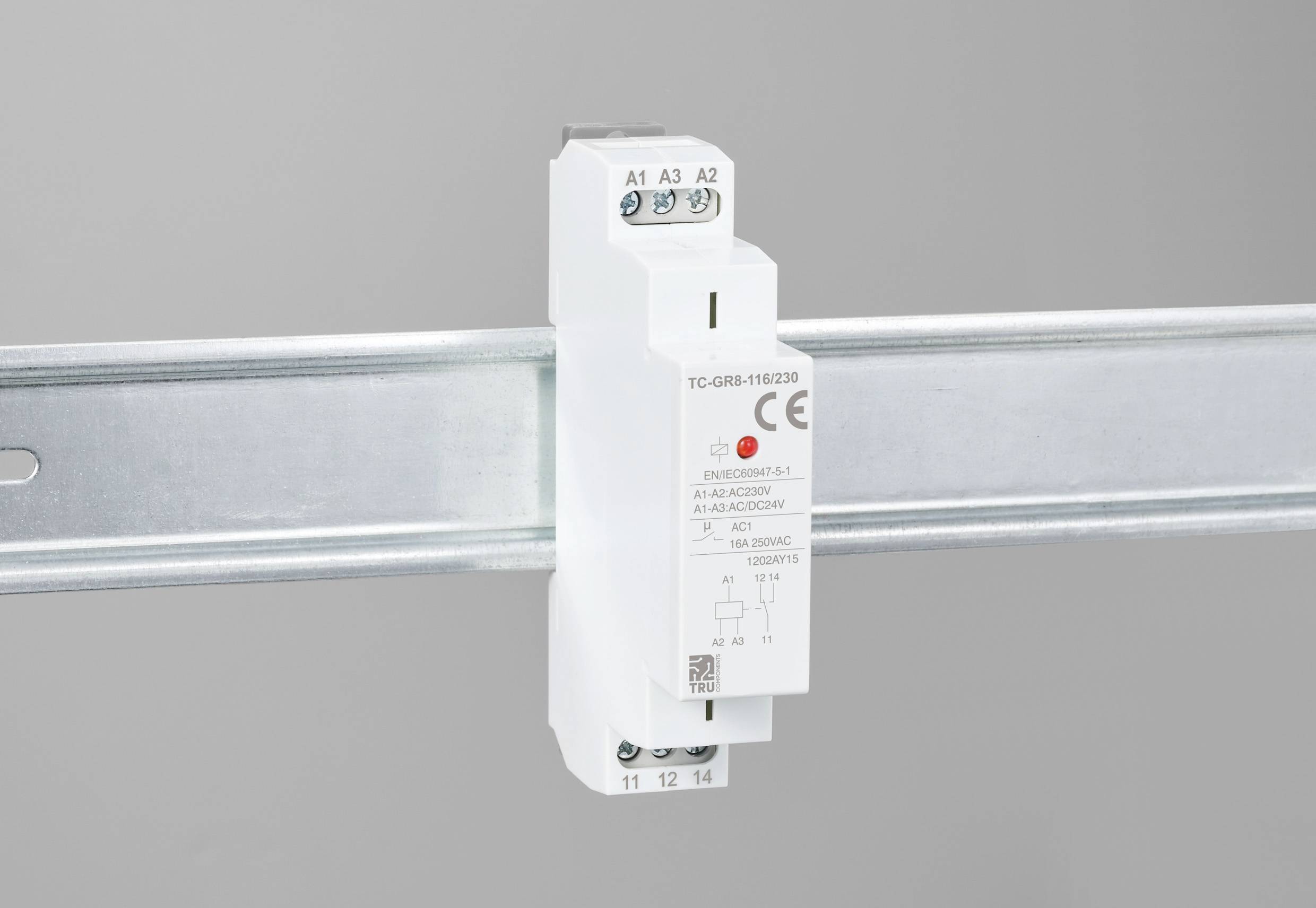 Un relais sur rail DIN blanc avec des bornes de connexion marquées et un marquage CE, monté sur un rail métallique.