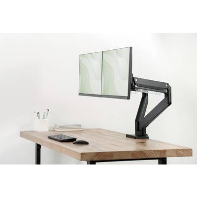 Un bureau en bois équipé de deux écrans sur un bras articulé, avec un clavier, une souris et un porte-stylos contenant des stylos ; un aménagement clair et minimaliste.