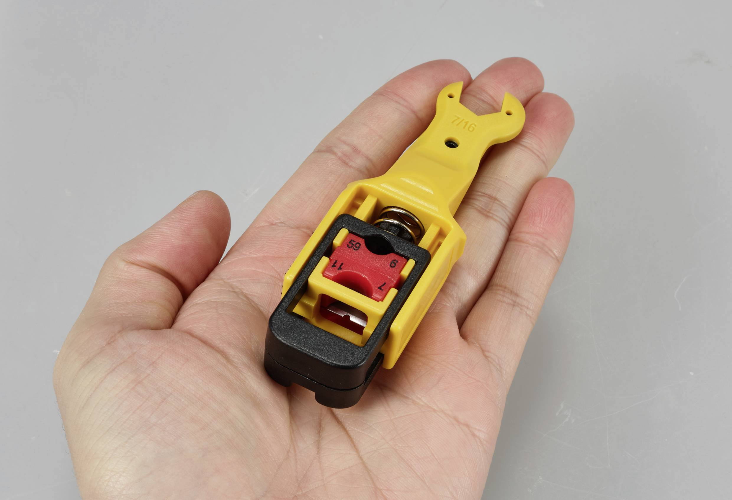 Une main tient un cadenas de sécurité jaune avec un détail rouge au centre.
