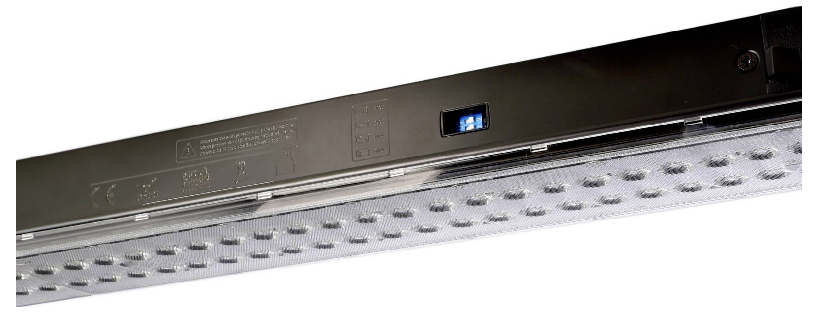 Gros plan d'un luminaire LED linéaire noir, avec des rangées de diodes et un petit écran numérique bleu sur le corps.