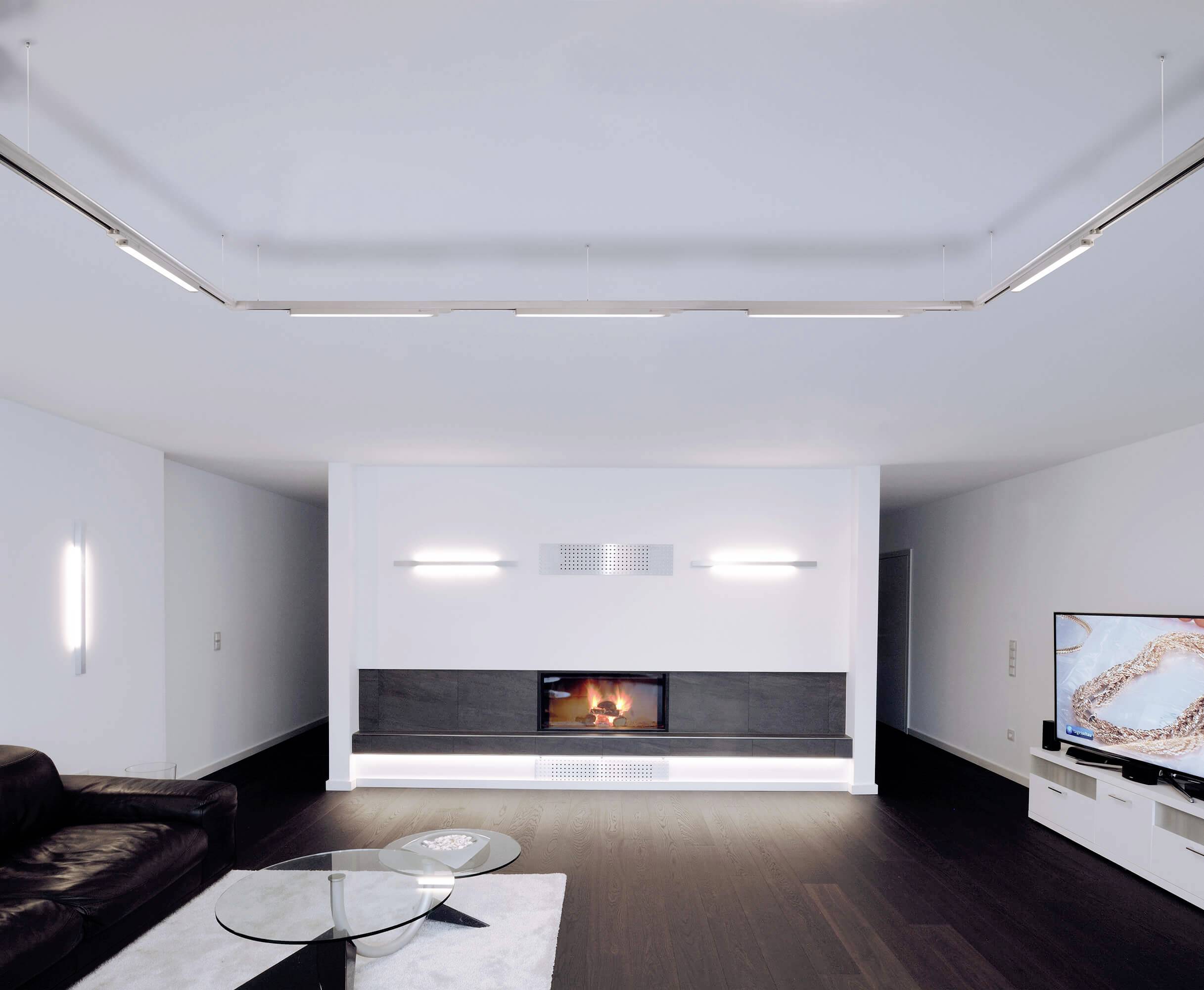 Salons modernes avec un parquet sombre, un canapé en cuir noir, une cheminée encastrée et un grand téléviseur à écran plat.