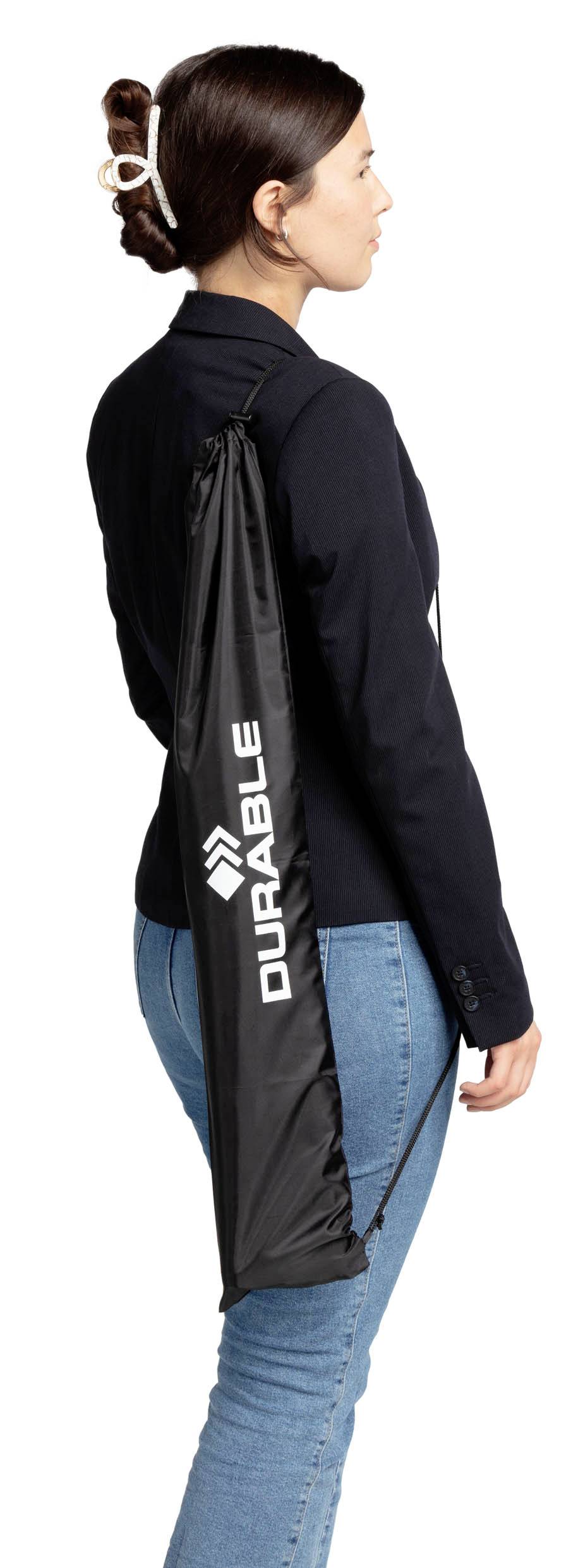 Une femme porte un sac cabas noir sur l'épaule avec l'inscription 'DURABLE'. Elle est vêtue d'un blazer noir formel.