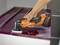 Une personne utilise un outil multifonction orange pour enlever de la peinture d'une surface.