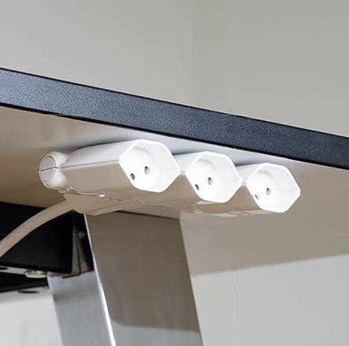 Barrette multiprises blanche montée sous une table, illustrant une solution de gestion de câbles organisée pour bureaux ou espaces de travail.