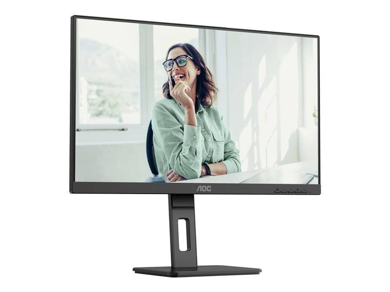 Un écran d'ordinateur montre une femme souriante portant des lunettes, vêtue d'une chemise verte, assise devant une fenêtre dans un bureau.