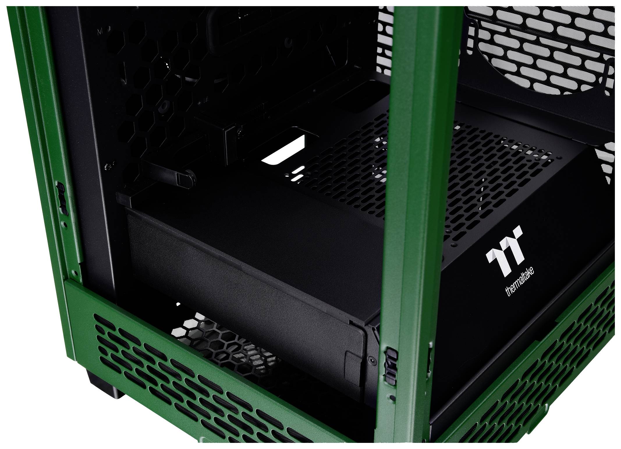 Boîtier d'ordinateur vert à l'intérieur avec une alimentation noire de marque Thermaltake. Design en maille visible pour la ventilation.