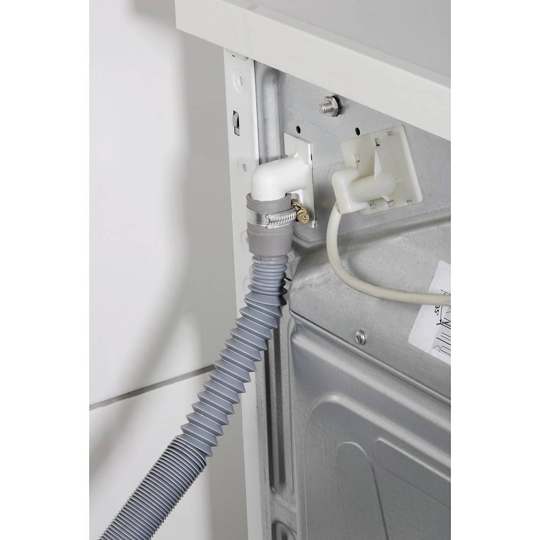 Vue arrière d'une machine avec un tuyau de vidange gris raccordé et un câble blanc branché dans une prise électrique.