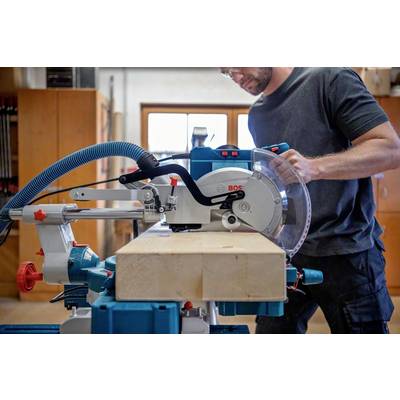 Une personne utilise une scie circulaire de table dans un atelier pour réaliser un travail du bois précis. Des outils sont visibles en arrière-plan.
