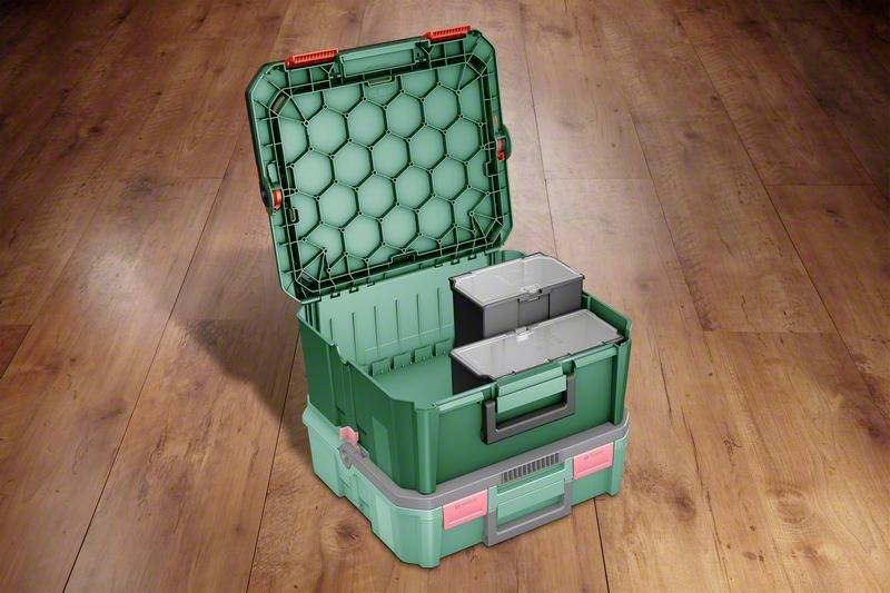 Boîte à outils verte avec couvercle ouvert sur un sol en bois, contenant deux récipients amovibles.