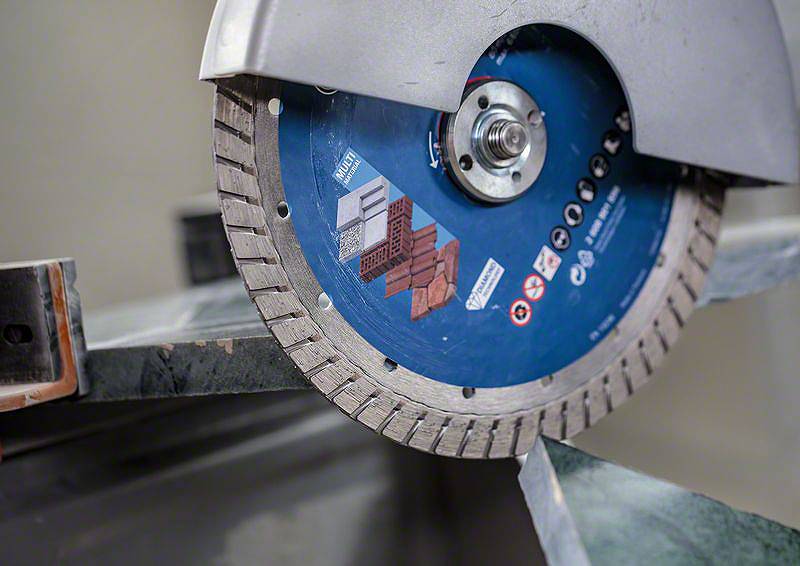 Un disque à tronçonner en diamant coupe une tôle. Un gros plan montre les détails du disque et le matériau découpé.