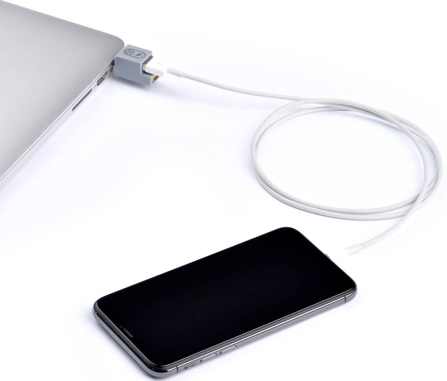 Un smartphone est connecté à un ordinateur portable via un câble USB, ce qui permet le transfert de données ou la recharge de l'appareil.