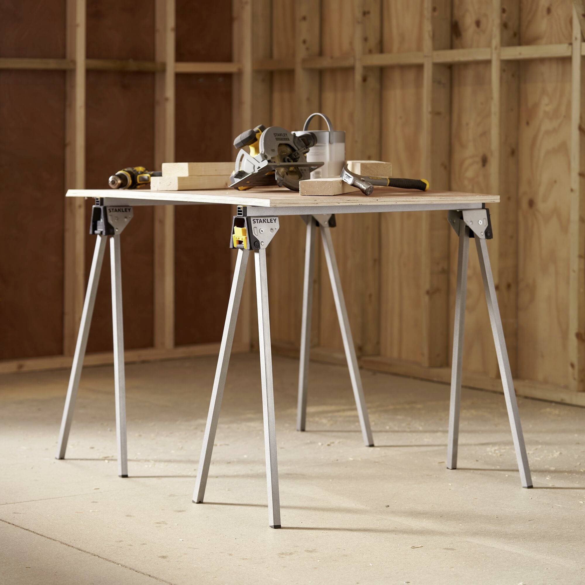 'Scies et planches de bois sur une table de travail dans un atelier de menuiserie, entourées de murs-cadres en bois inachevés.'