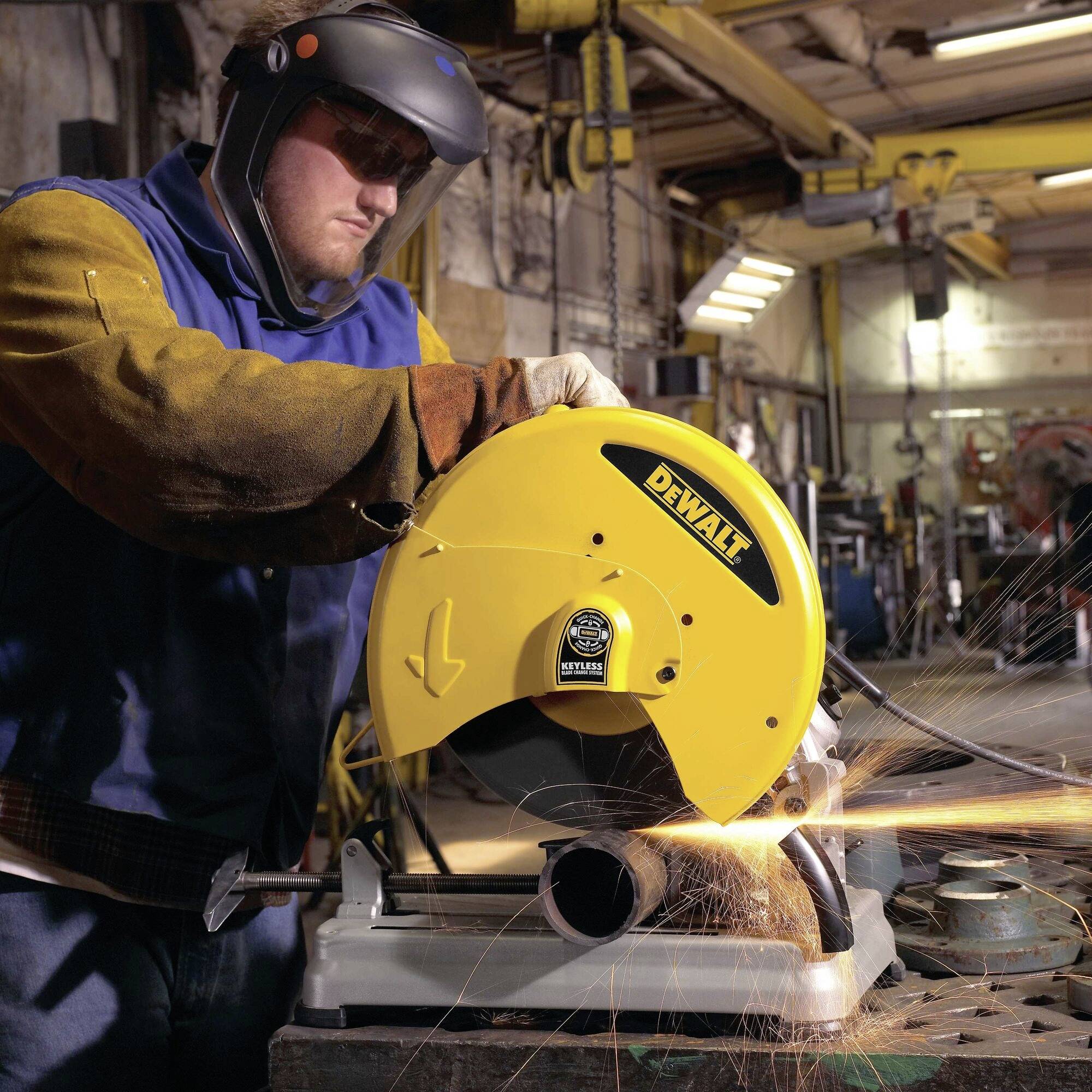Un travailleur équipé d'un équipement de protection coupe un tuyau métallique avec une machine DeWalt dans un environnement d'atelier industriel.